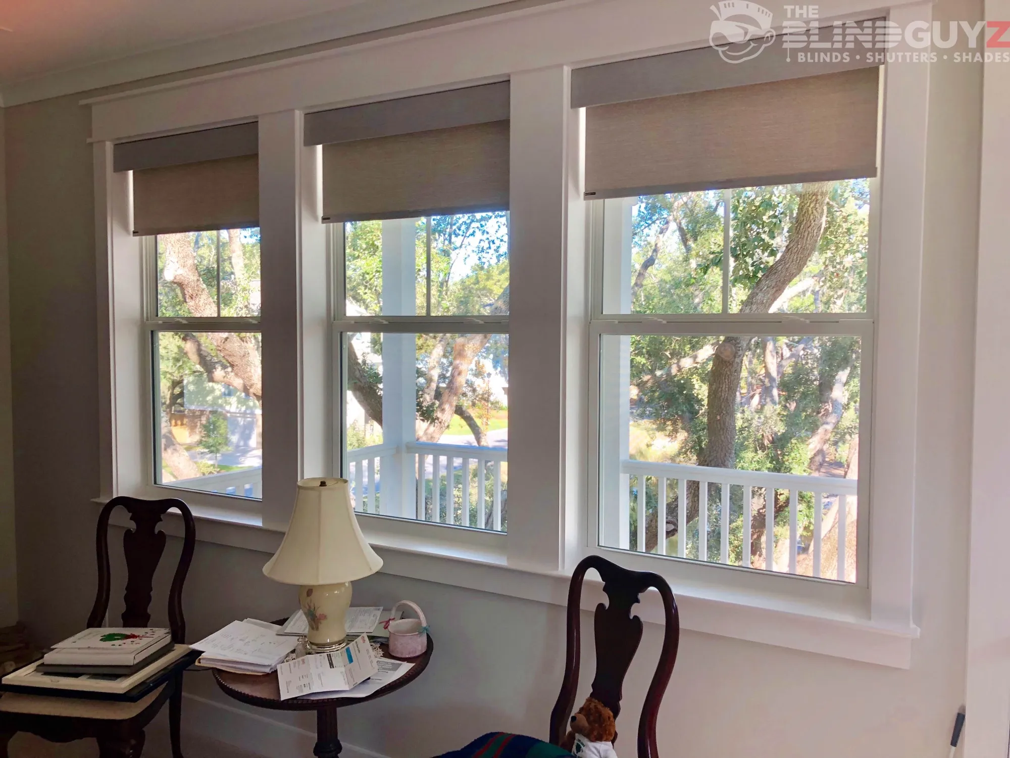Taupe roller shades with matching fascias, raised high on three double-hung windows.