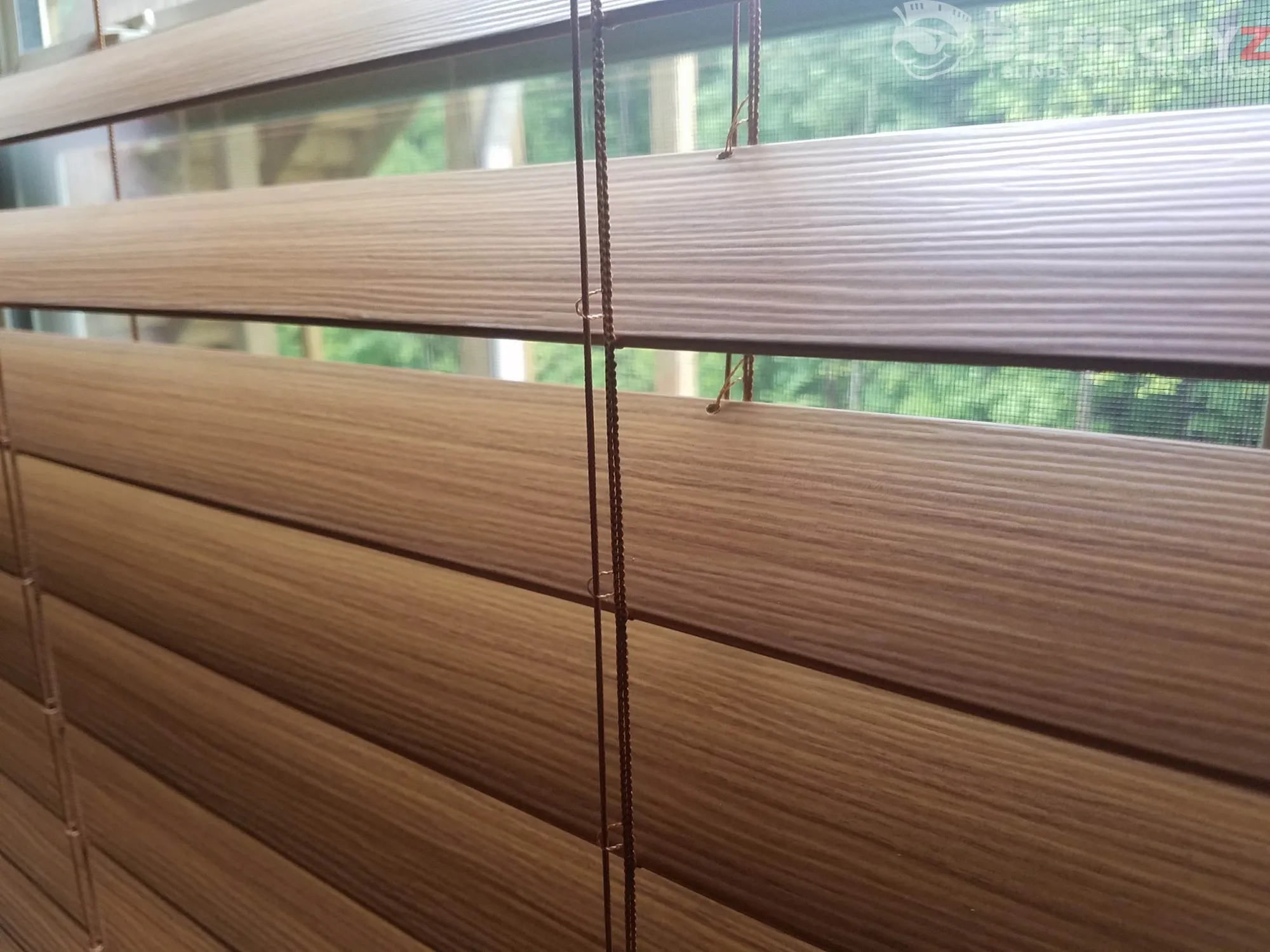 Close-up of wood-grain blind slats, tilted partly open.