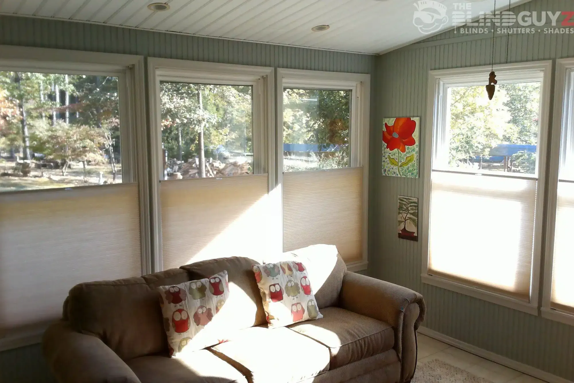 Cream top-down, bottom-up cellular shades lowered from the top on the windows of a sunroom.