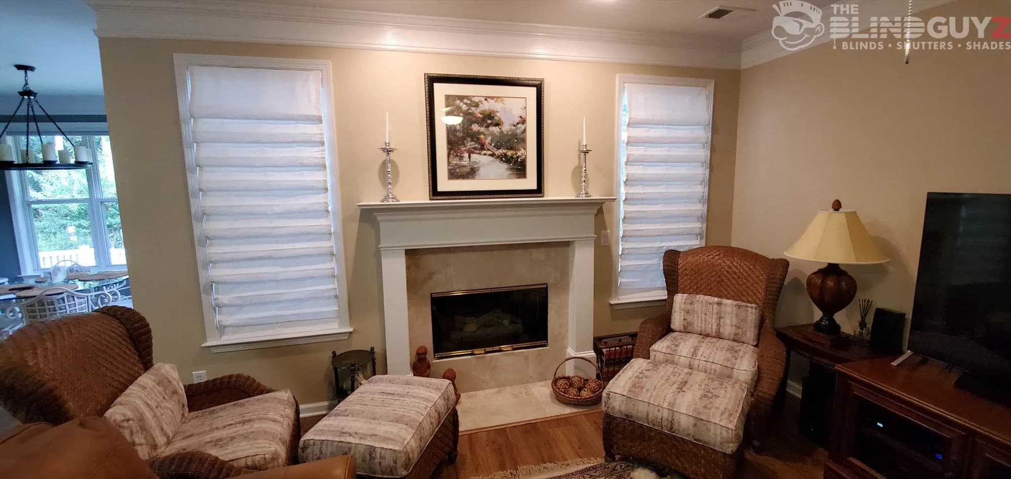 White roman shades in a soft, cascading fold on the windows either side of a fireplace.