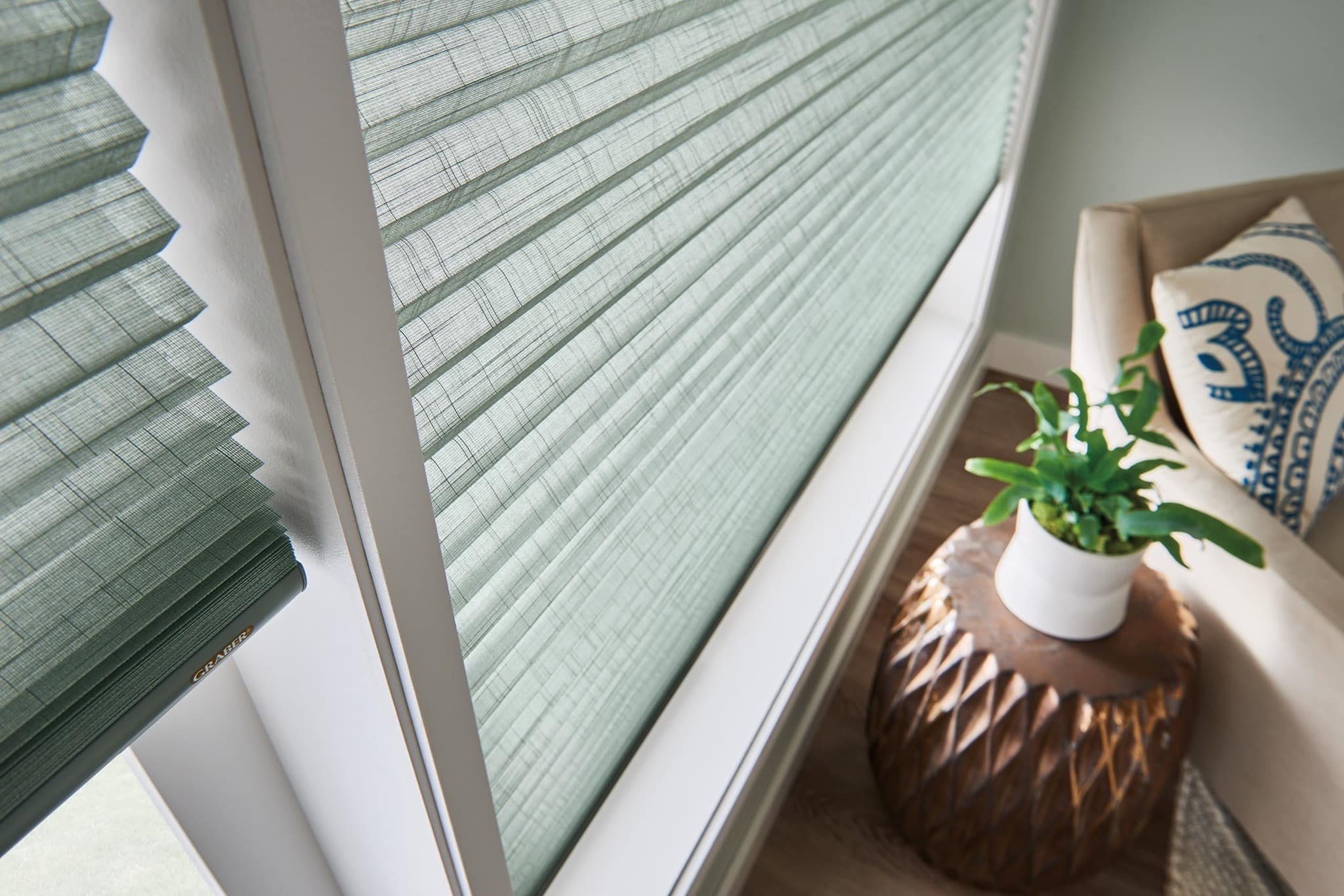 Sage green cellular shades filtering daylight in a living room